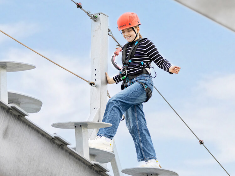 Eine Jugendliche erklettert stolz den SkyTrail Klettersteig und setzt einen Fu� vor den anderen