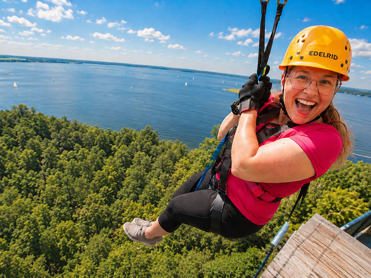 Eine Frau startet aufgeregt lachend in ihre Fahrt mit der Zipline