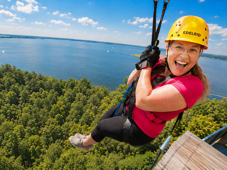Eine Frau startet aufgeregt lachend in ihre Fahrt mit der Zipline